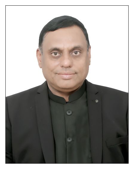 Man in a black suit with a buttoned shirt, posed against a white background.